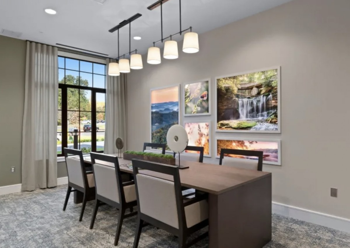 A modern dining room with elegant lighting and framed artwork on the walls.