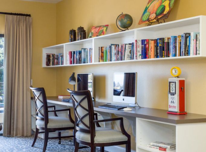 A well-organized home office workspace with computers and a bookshelf.