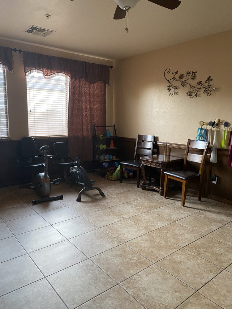 A room with exercise equipment, a table with chairs, and decorative elements.