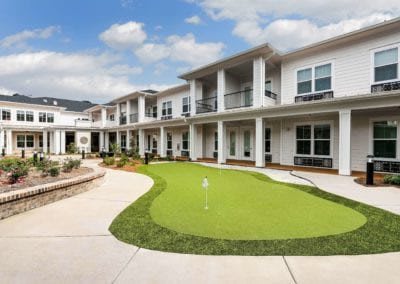A modern residential building with a landscaped outdoor area, featuring a golf putting green.