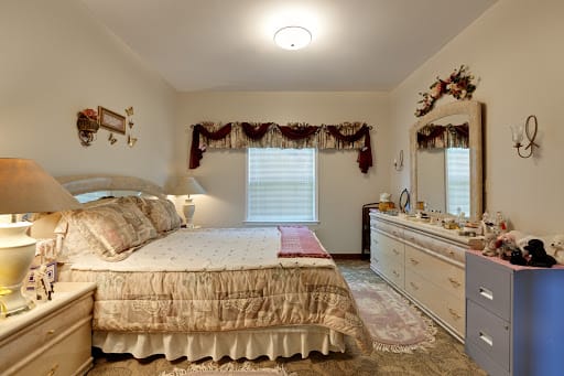 A traditionally styled bedroom with a bed, dresser, and decorative elements.