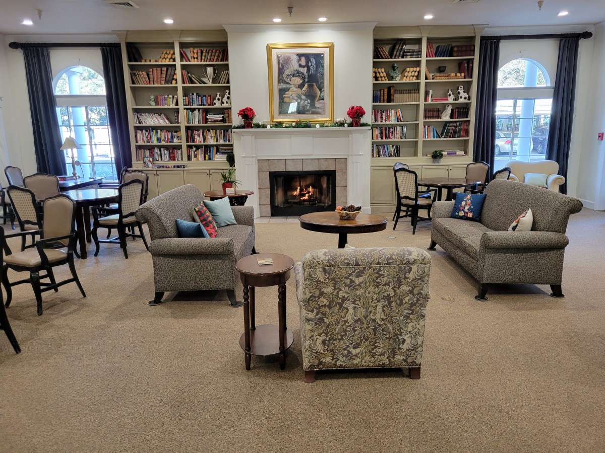 A cozy library with bookshelves, a fireplace, and comfortable seating.