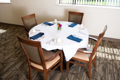 A neatly set dining table with four chairs and a decorative centerpiece.