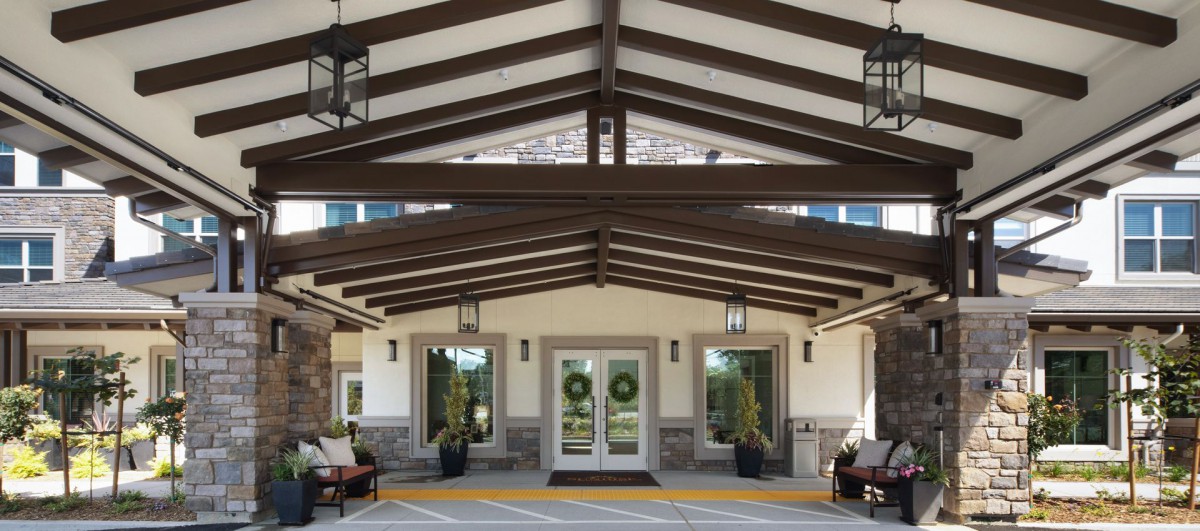 A symmetrical building entrance with a covered walkway and outdoor seating.