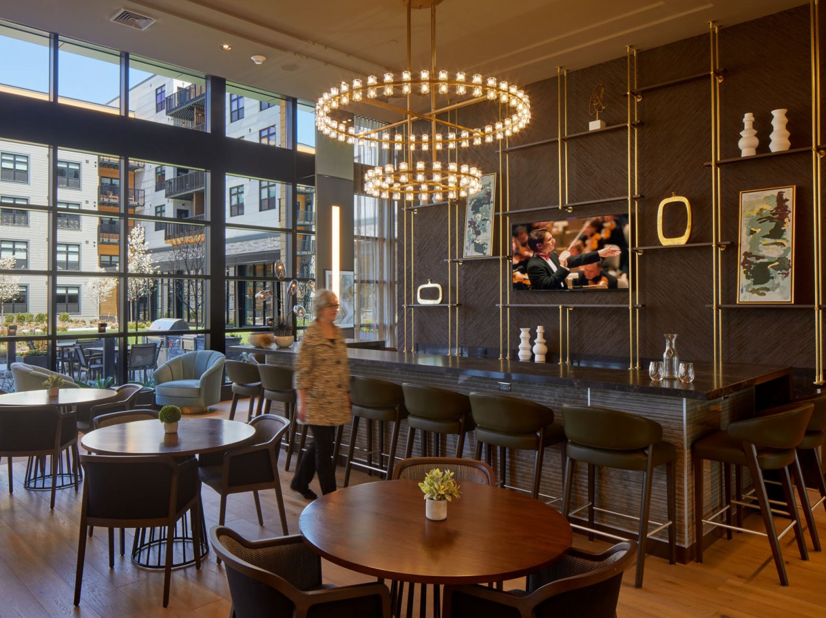 A modern restaurant interior featuring elegant chandeliers and a stylish bar area with comfortable seating.