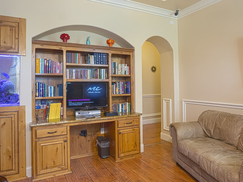 A cozy living room featuring a wooden bookshelf with books and a television, alongside a comfortable sofa.