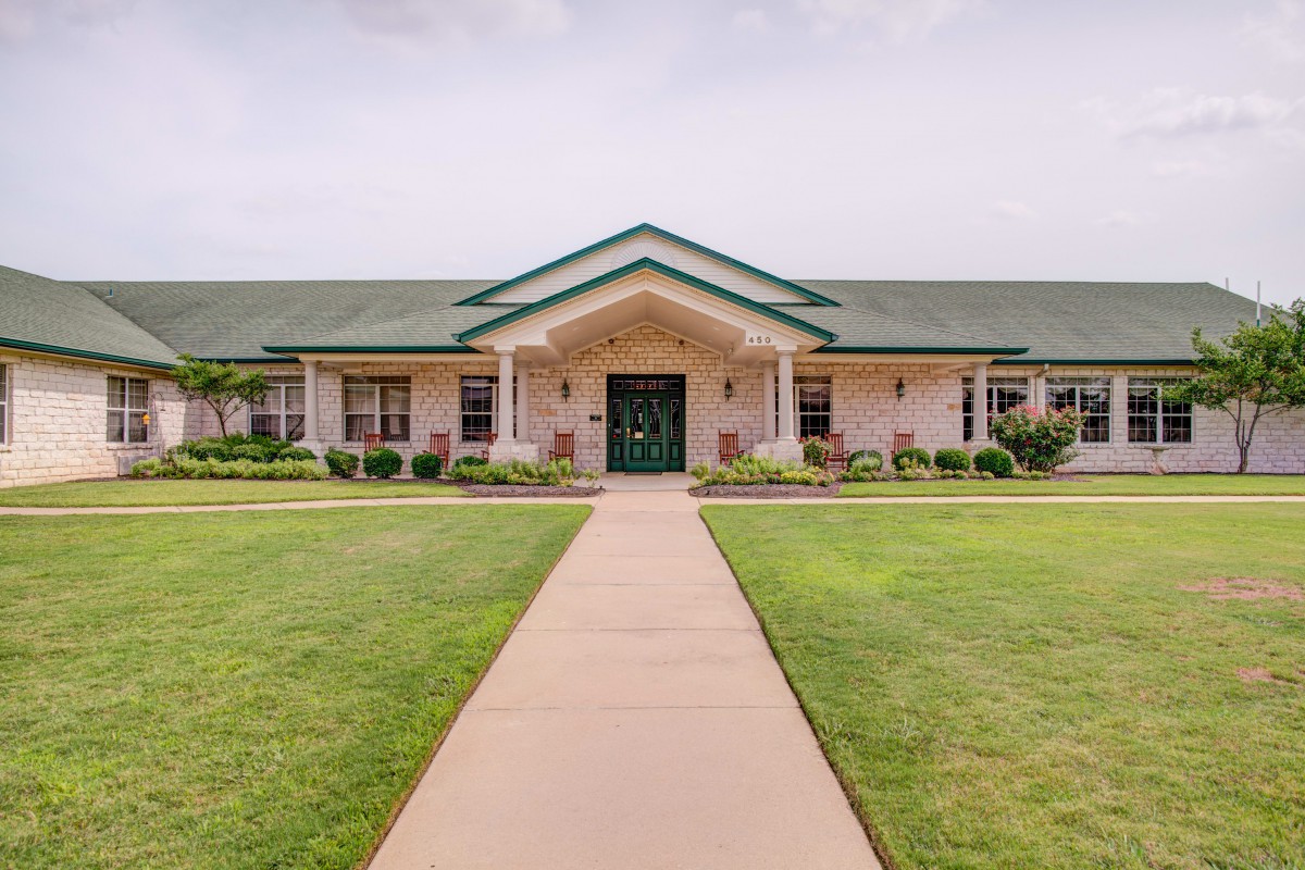 A single-story building with a green roof and well-maintained lawn.