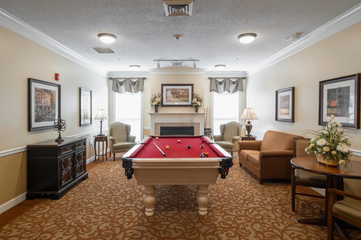 A cozy recreation room featuring a billiard table and comfortable seating around a fireplace.