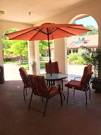 A cozy outdoor seating area featuring a table with an umbrella and colorful chairs, perfect for enjoying the fresh air.