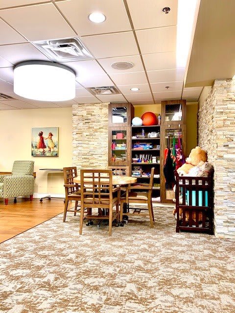 A cozy room with a table and chairs, surrounded by cabinets and soft lighting.