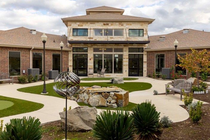 A modern building with a landscaped courtyard featuring pathways and ornamental plants.