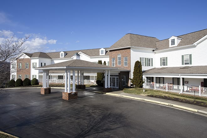 A large commercial building with an entrance and driveway under a clear blue sky.