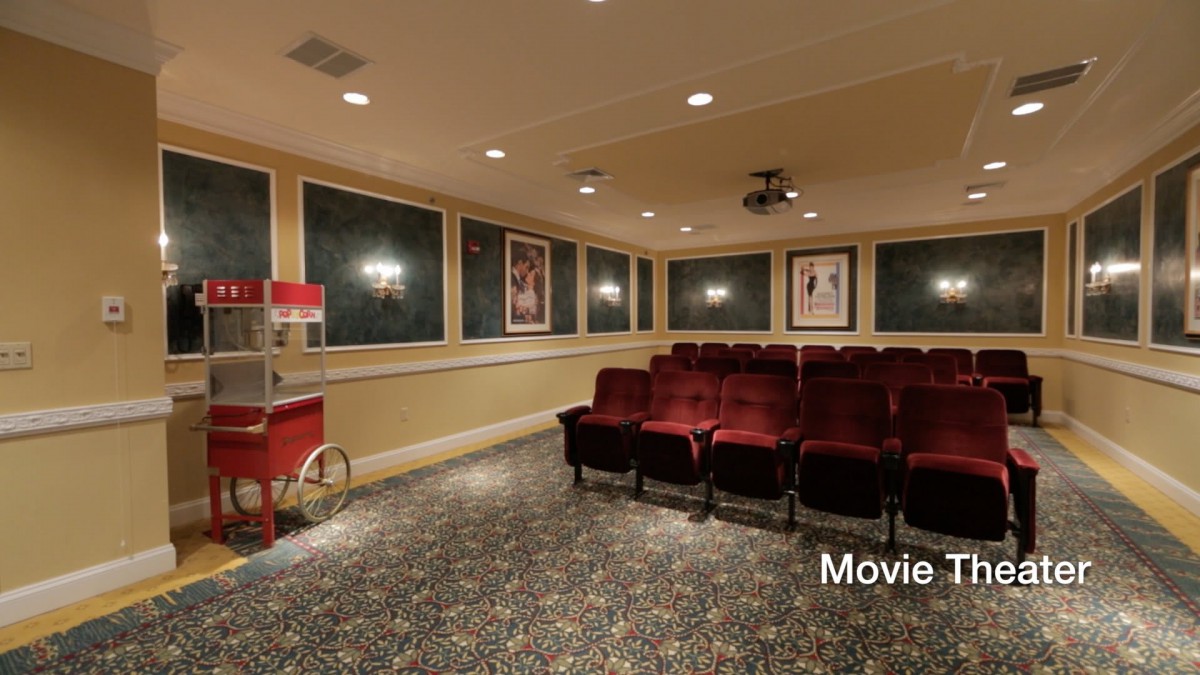 A cozy home theater setup with red seating, movie posters, and a popcorn machine.
