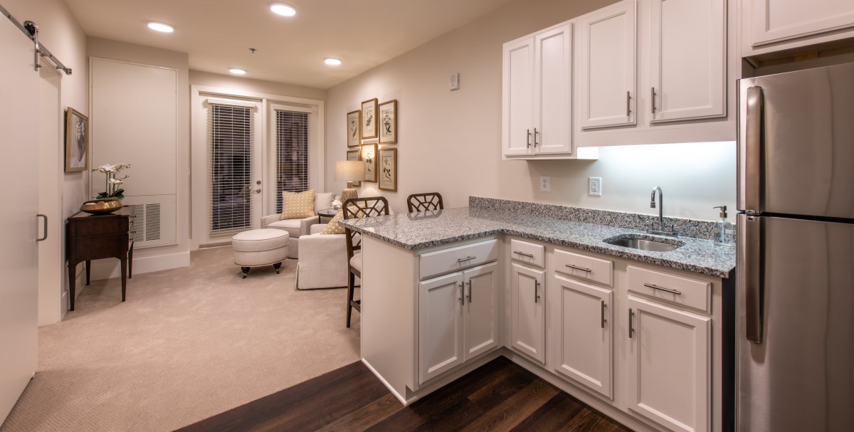 A modern open-concept kitchen and living area featuring white cabinets and tasteful decor.