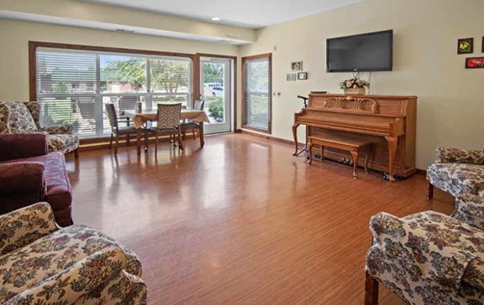 A spacious living room with a piano, dining table, and large windows allowing natural light to fill the space.