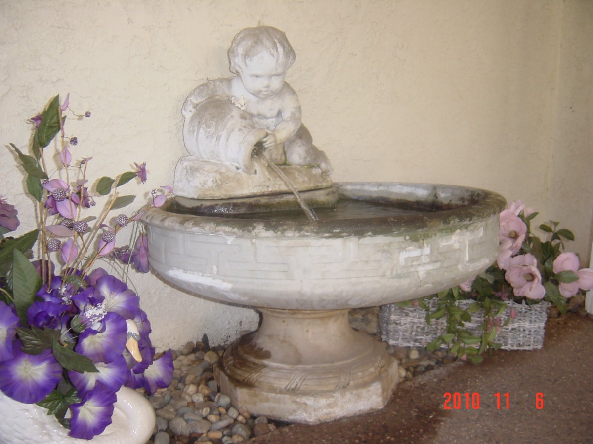A decorative garden fountain with a statue of a child pouring water.