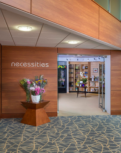 A welcoming entrance to a store named 'necessities', adorned with fresh flowers and modern interior design.