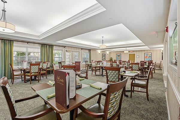 A well-lit dining room with neatly arranged tables and chairs, featuring menus on the tables.