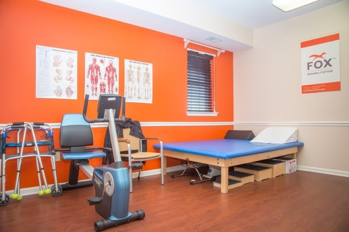 A physical therapy room equipped with exercise equipment and a therapy bed, designed for rehabilitation sessions.