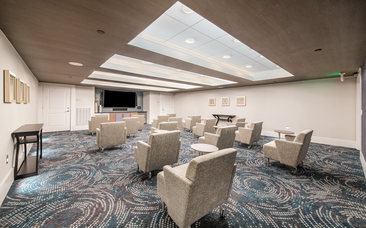 A modern lounge area featuring comfortable armchairs and a large television screen.