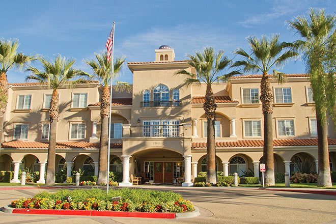 A building with palm trees and an entrance featuring an American flag.