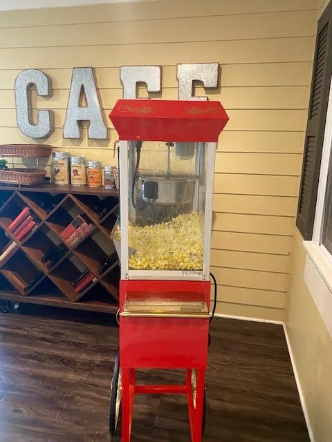 A red popcorn machine is placed in a cafe setting, ready to serve freshly popped corn.
