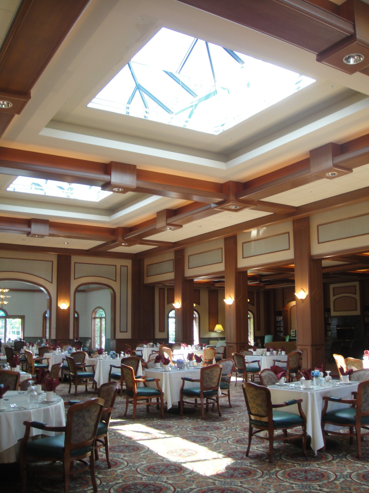 An elegant dining area with tables set and a skylight overhead.