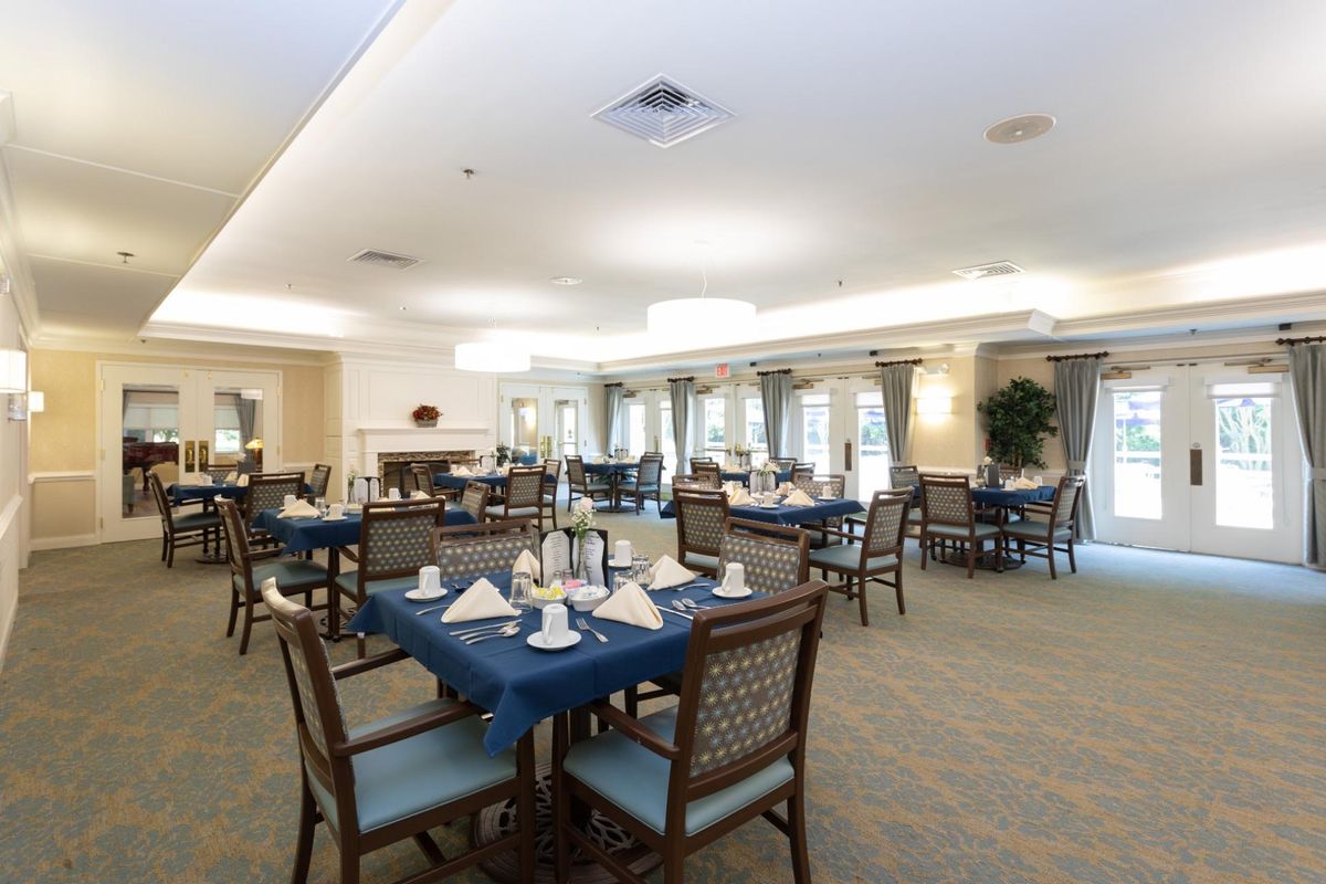 A well-lit dining room with neatly arranged tables and chairs, set for a meal.