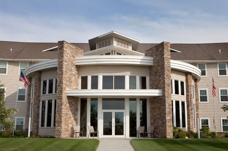A modern building facade with large windows and stonework accents.