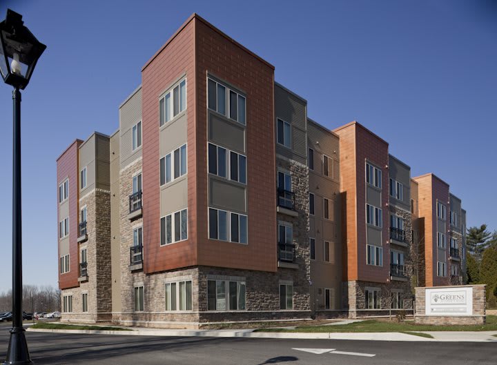 A modern apartment building with a brick facade and multiple stories, located in an urban area.