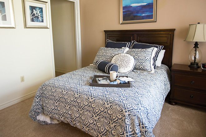A neatly arranged bedroom with patterned bedding and a decorative tray on the bed.