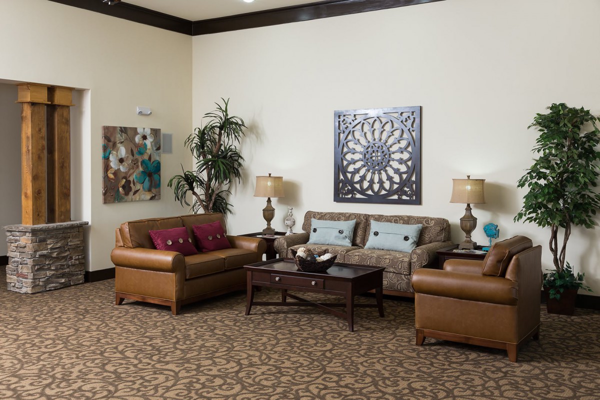 A cozy living room with leather sofas, a central coffee table, decorative lamps, and wall art.