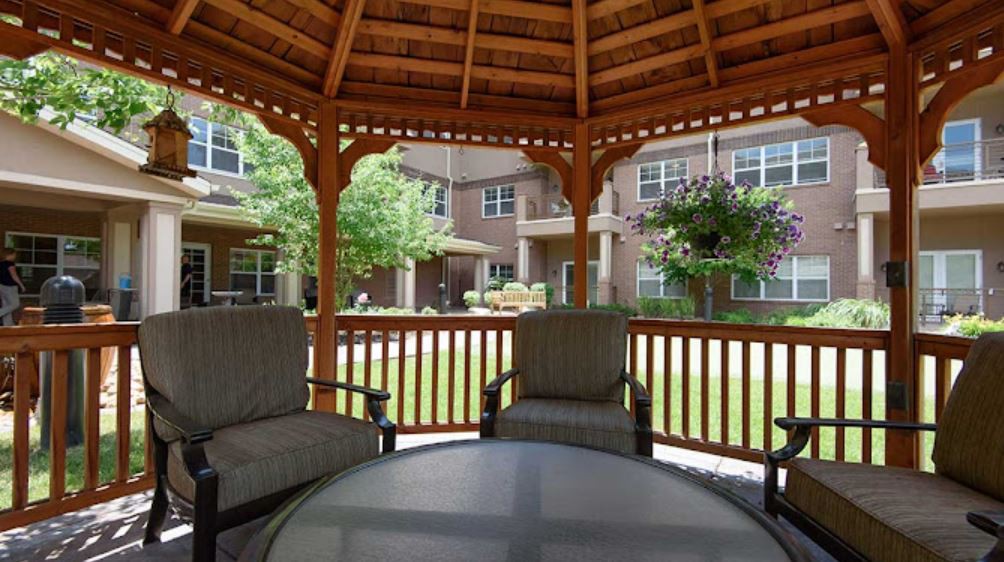 A cozy gazebo with comfortable chairs in a garden setting at an apartment complex.