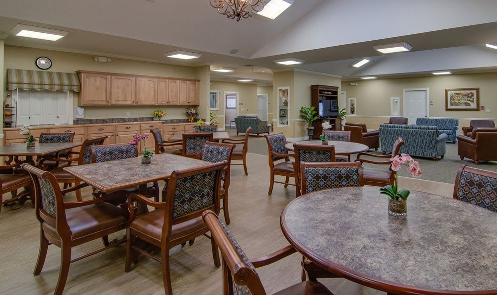 A spacious community dining area with multiple tables and chairs, featuring warm lighting and wood furnishings.