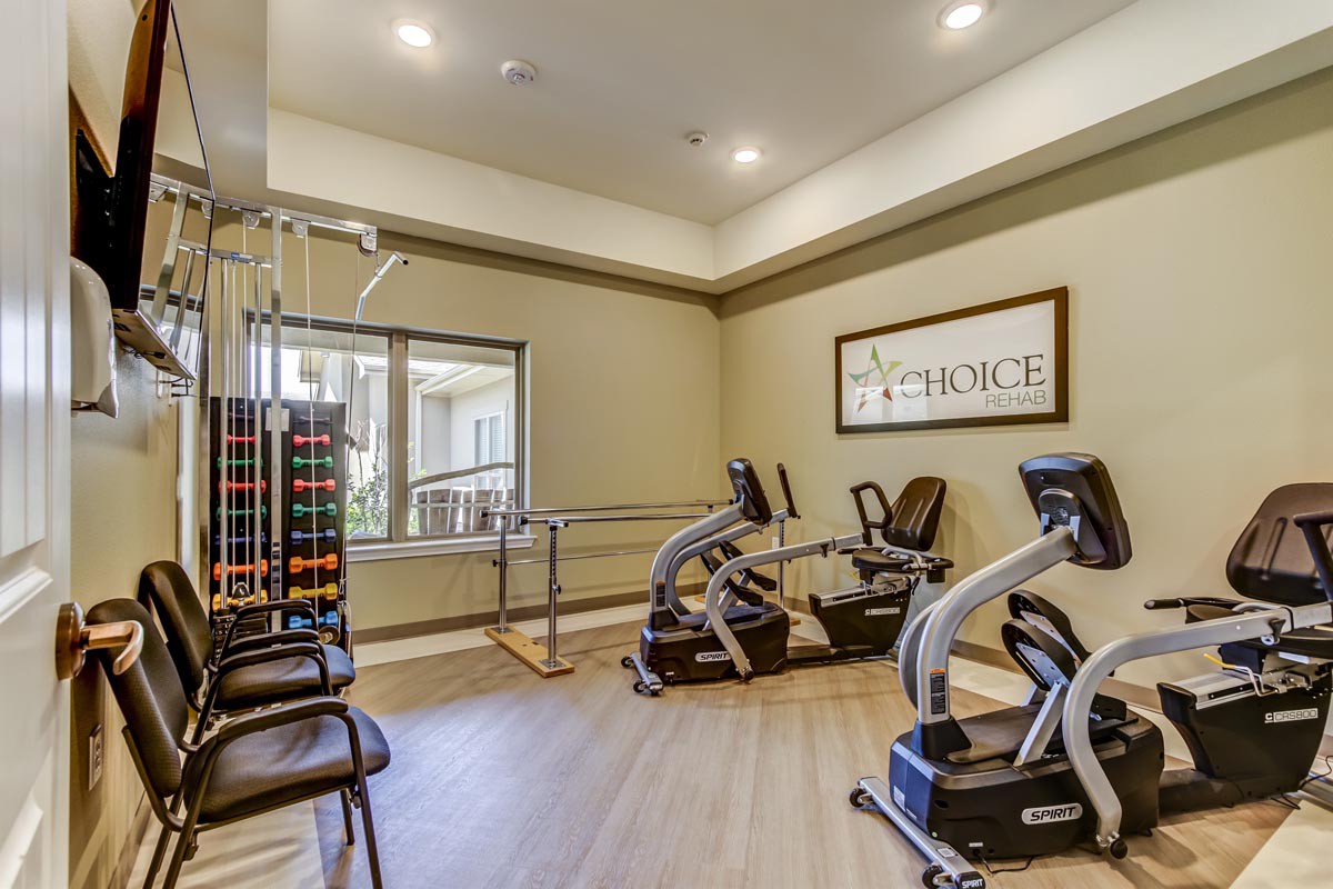 A well-equipped gym with recumbent bikes and a rack of dumbbells.