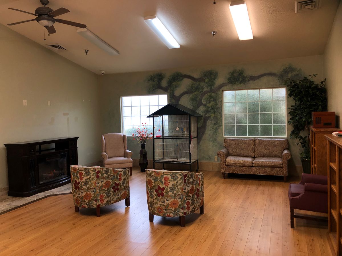 A cozy living room with a seating area, featuring a sofa, chairs, and a fireplace.