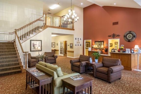 A spacious and comfortable lobby with seating areas, a staircase, and a chandelier.