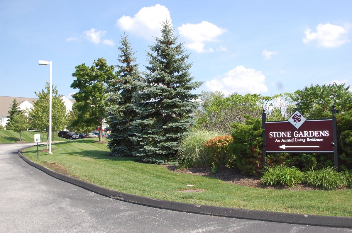 A scenic outdoor view featuring a road, trees, and a sign indicating the Stonebridge community.