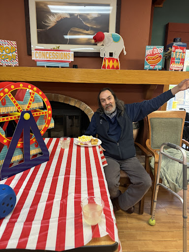 A man enjoying refreshments at a festive indoor carnival-themed gathering.