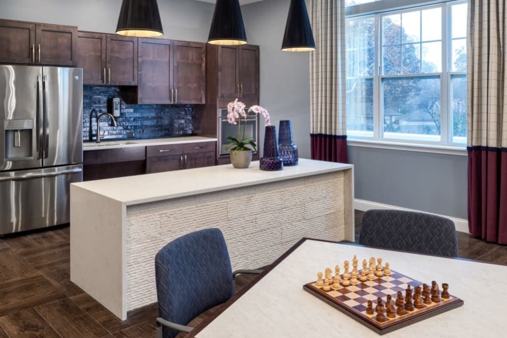 A modern kitchen interior with a chessboard on the table and elegant lighting.