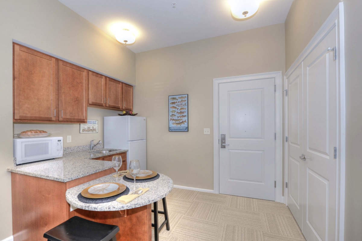 A cozy kitchen with wooden cabinets, a table with stools, and a white refrigerator.