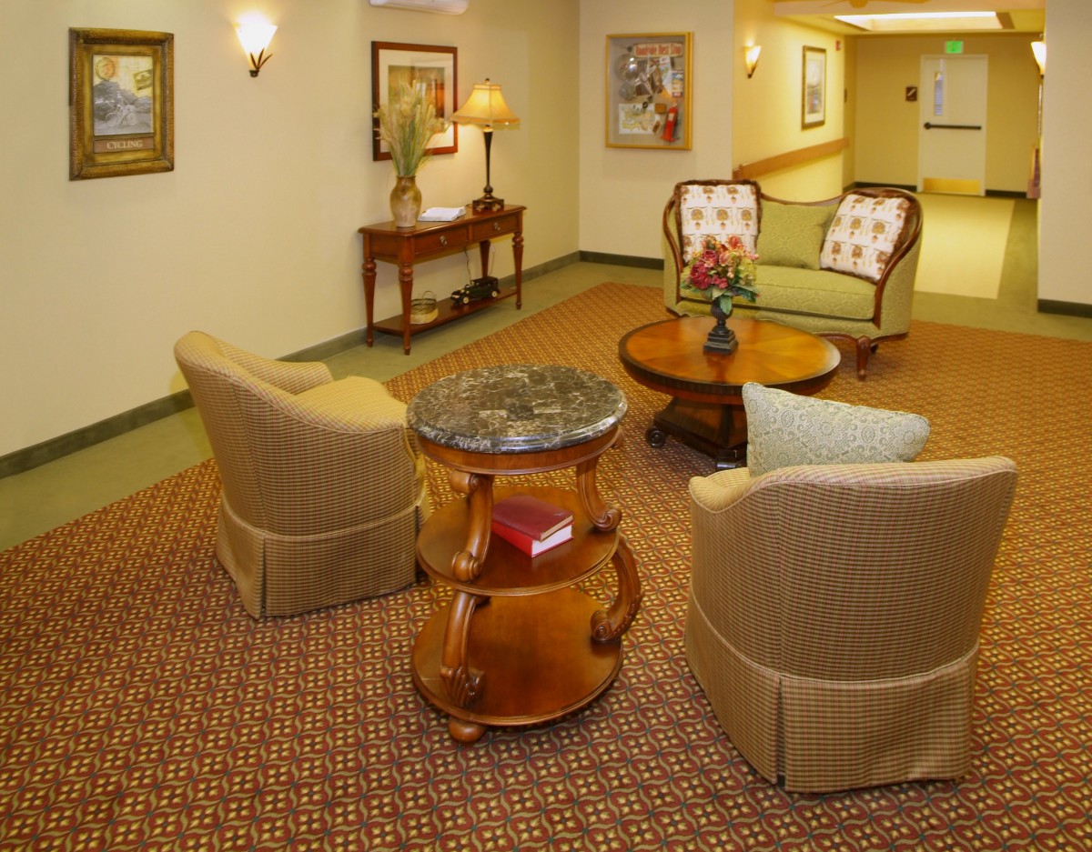A cozy lobby seating area with comfortable chairs, wooden tables, and decorative art on the walls.