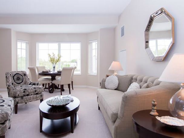 A bright and modern living room with elegant furniture, featuring a cozy sofa, a stylish coffee table, and a dining area by the window.