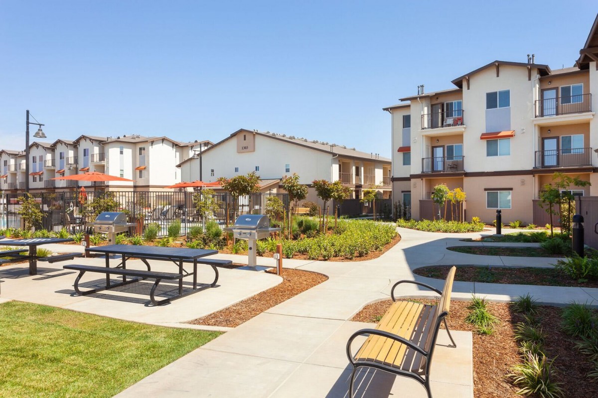 A modern apartment complex with landscaped pathways and outdoor seating areas.