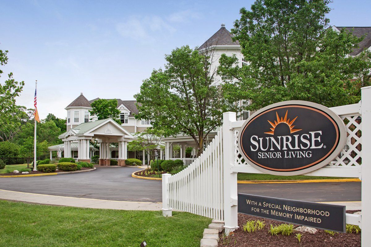 A picturesque view of a senior living facility, surrounded by greenery and featuring a welcoming entrance sign.