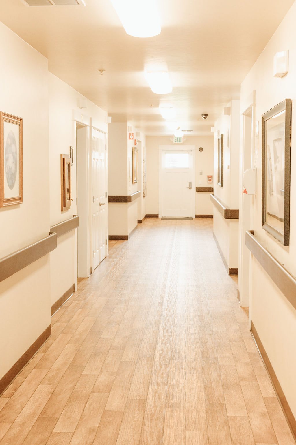A bright and clean hospital hallway with framed artwork on the walls.