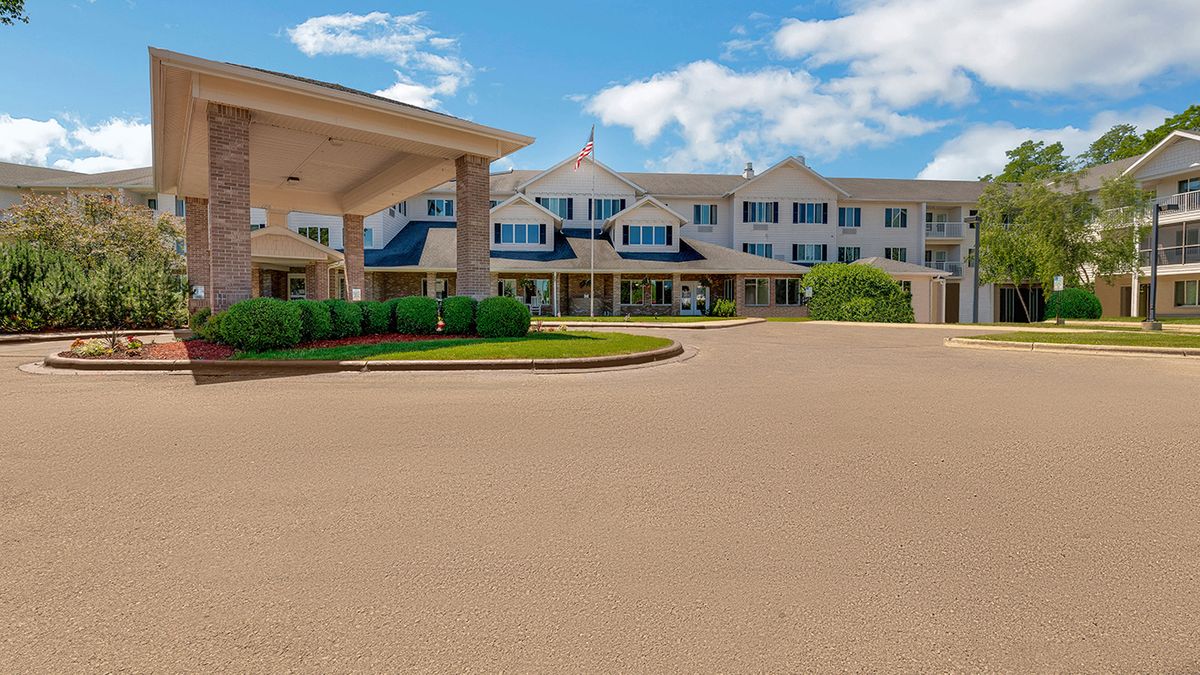 A large hotel building with a covered entrance and driveway under a partly cloudy sky.