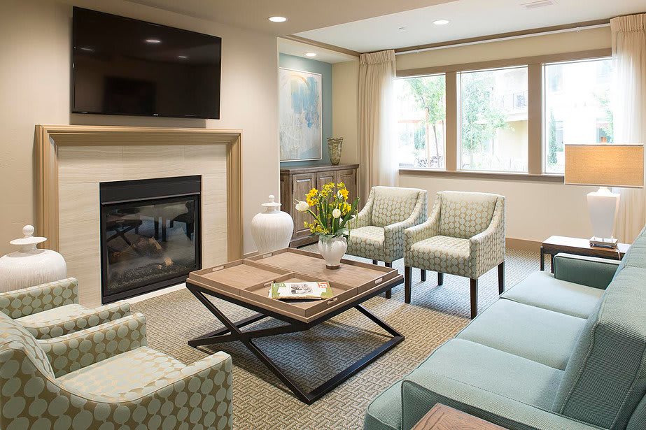A modern living room with a cozy seating area, featuring a fireplace and ample natural light.