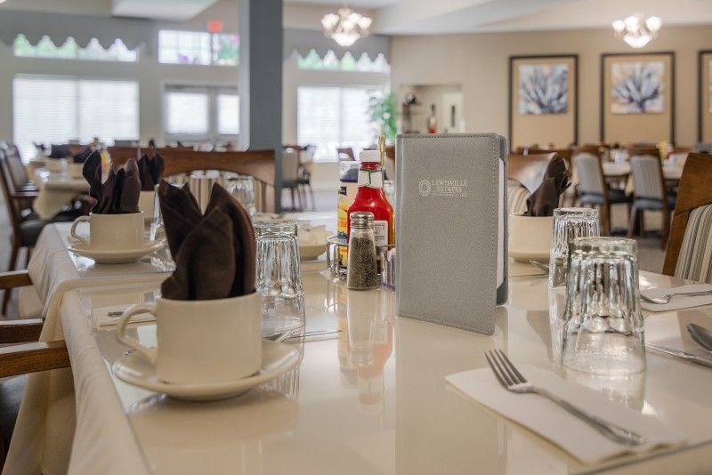 A neatly set restaurant table with a menu, napkins, glasses, and condiments.