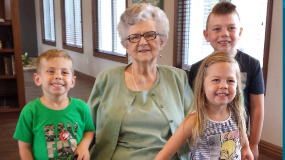 A grandmother with her three smiling grandchildren.